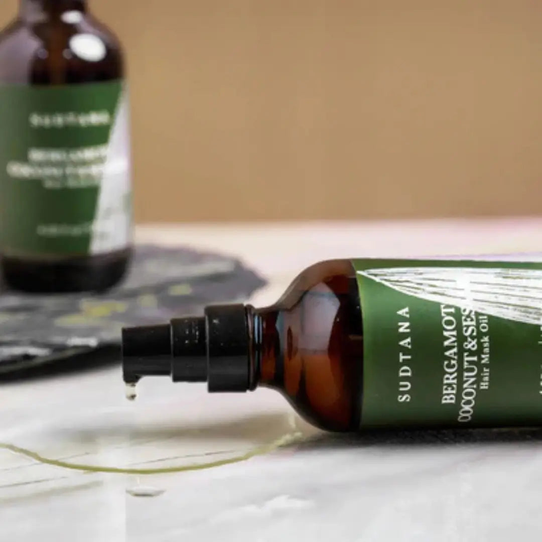 Sudtana hair mask oil bottle lying on its side, showing product's natural drip, ideal for hair revitalization.