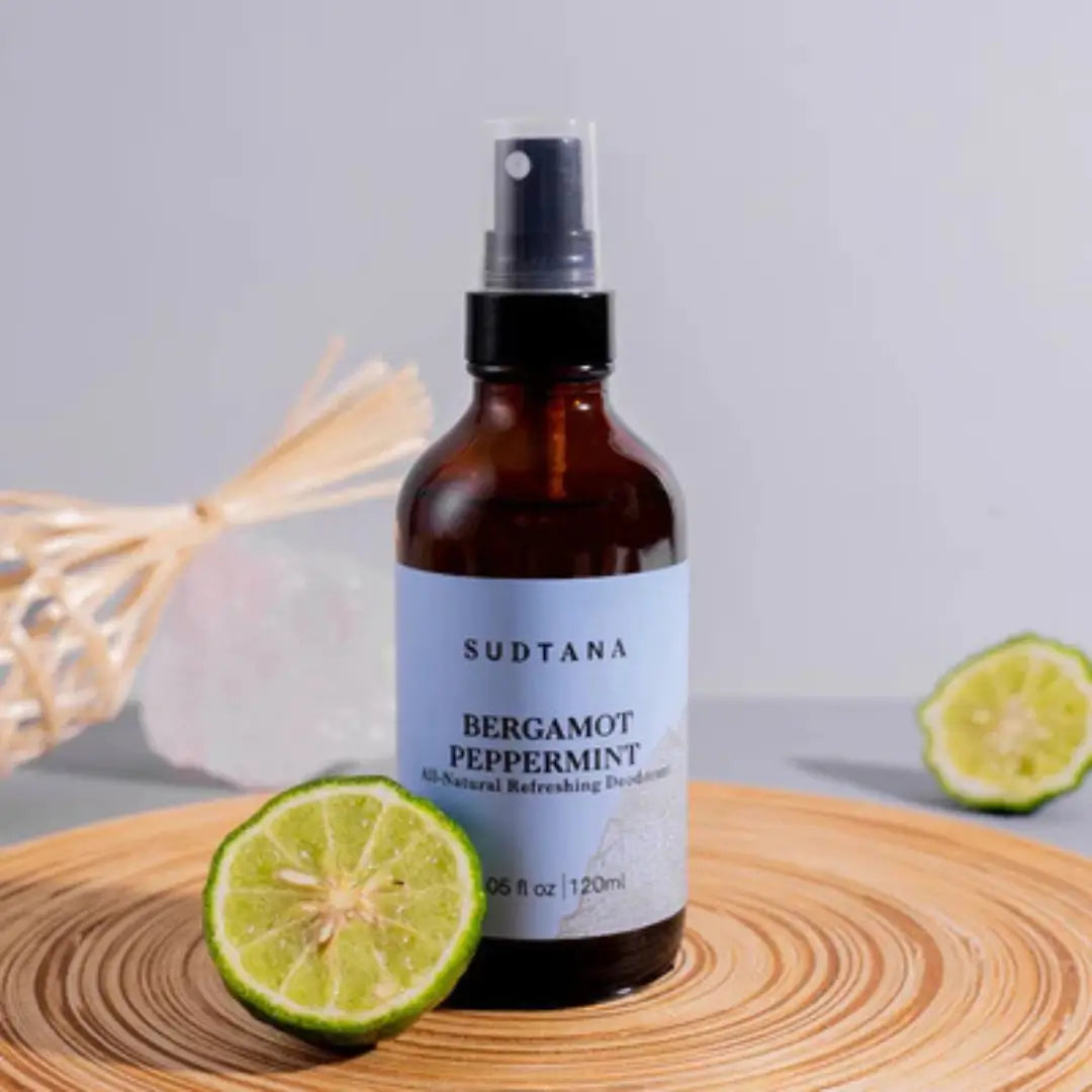 Sudtana bergamot peppermint deodorant spray on wooden surface, paired with sliced lime, for natural freshness.