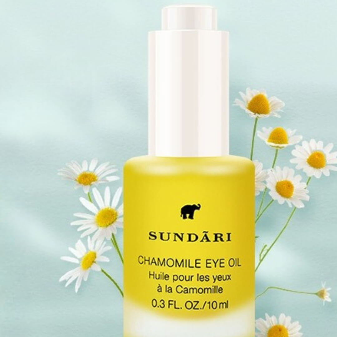 Sundari Chamomile Eye Oil bottle against a backdrop of chamomile flowers.