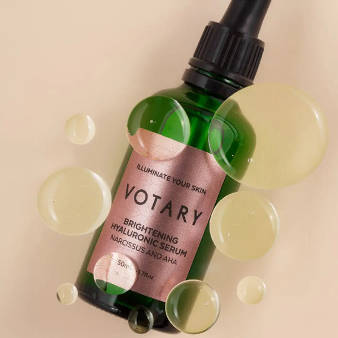 Votary Brightening Hyaluronic Serum bottle with scattered serum drops, highlighting its brightening properties for radiant skin.